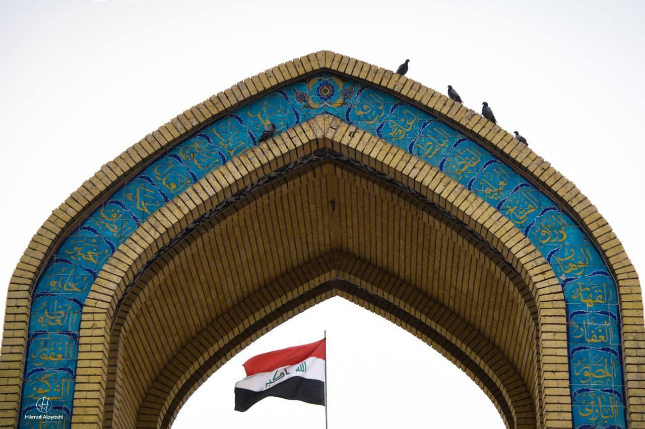 Iraqi flag framed beneath a decorated brick arch