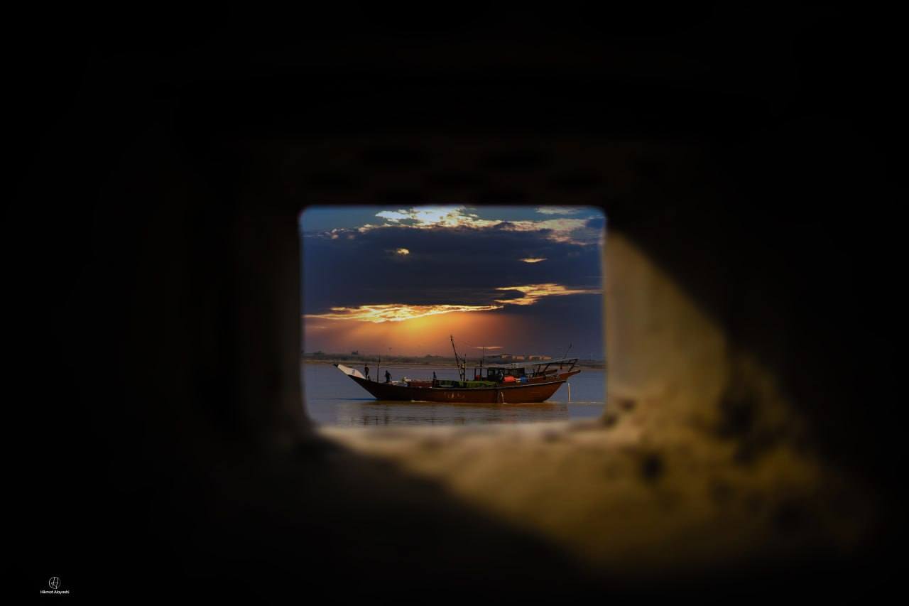 boat at sunset framed through a small window in Basra