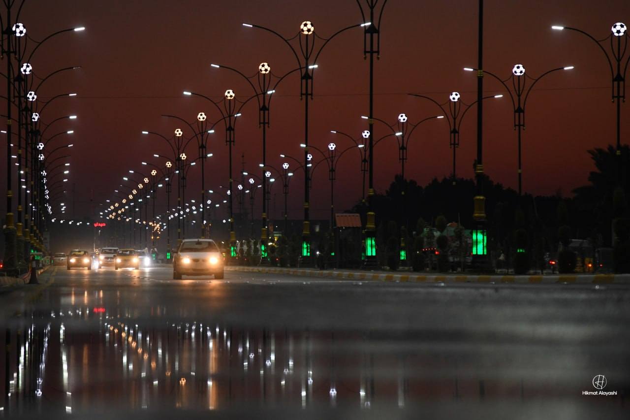 city street at night with glowing streetlights and cars
