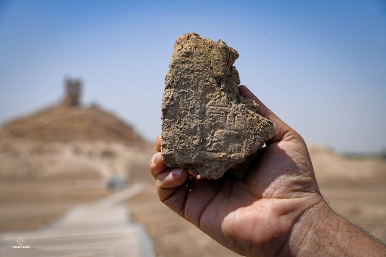 hand holding a stone with ancient Sumerian cuneiform writing in Iraq